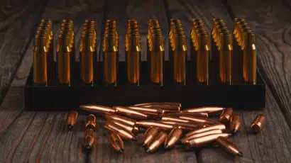 Organized brass cartridges and scattered copper bullets on dark wood, highlighting firearm dynamics.