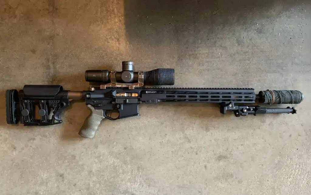 Tactical rifle with adjustable stock, precision scope, and suppressor for enhanced shooting performance.