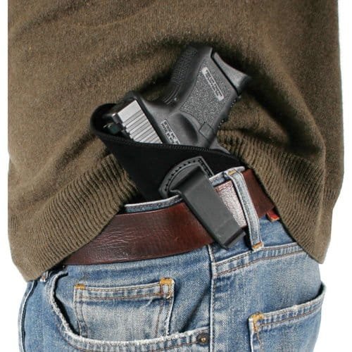 Concealed carry style featuring a holstered firearm, faded jeans, and a loose green shirt.